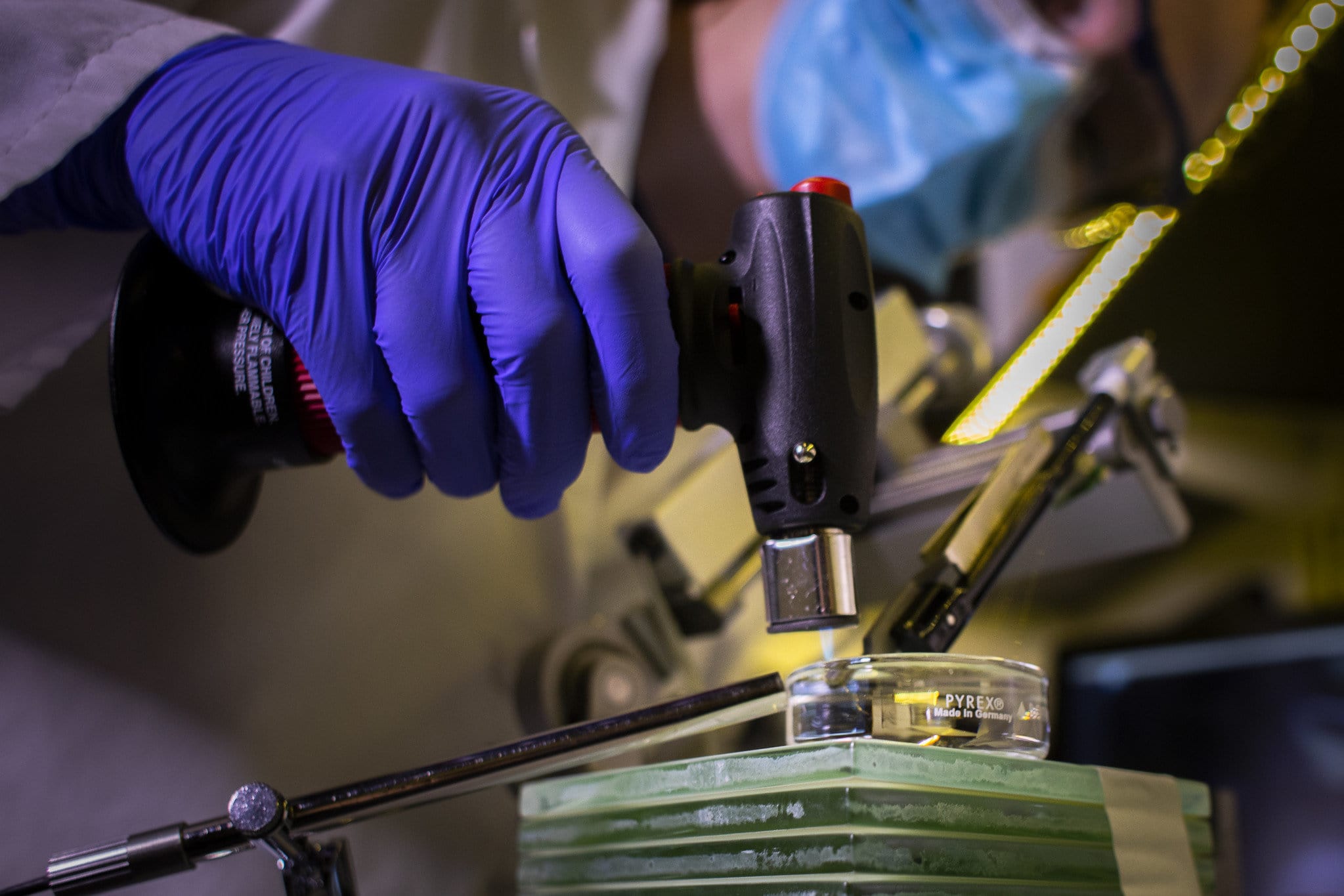 a person using a blow torch to heat something in a Petri dish