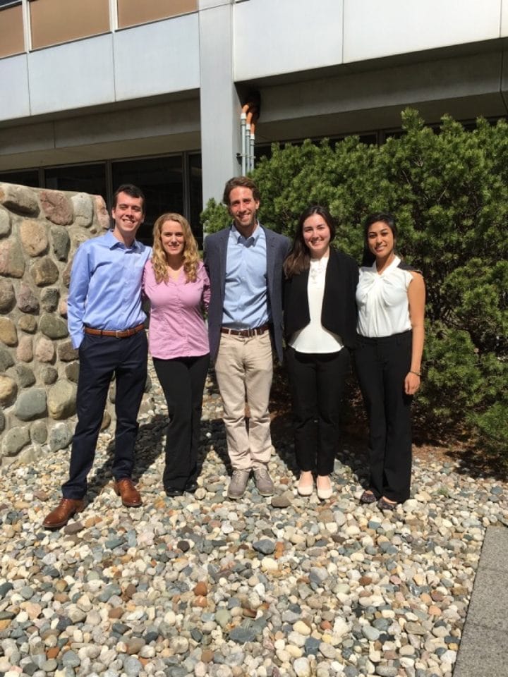 A group of five people standing in front of a building on small stones