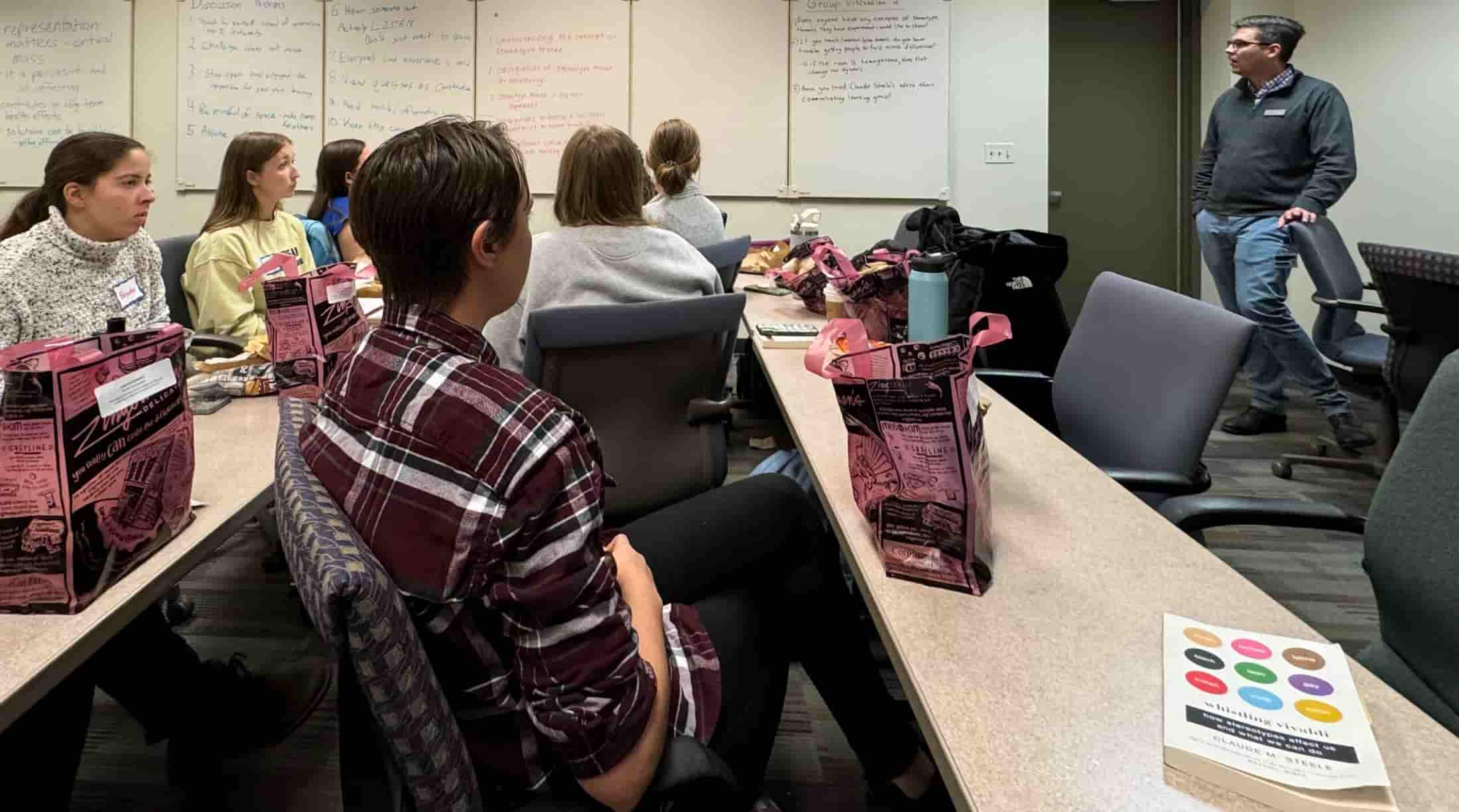 a group of students, staff and faculty listening to a presentation