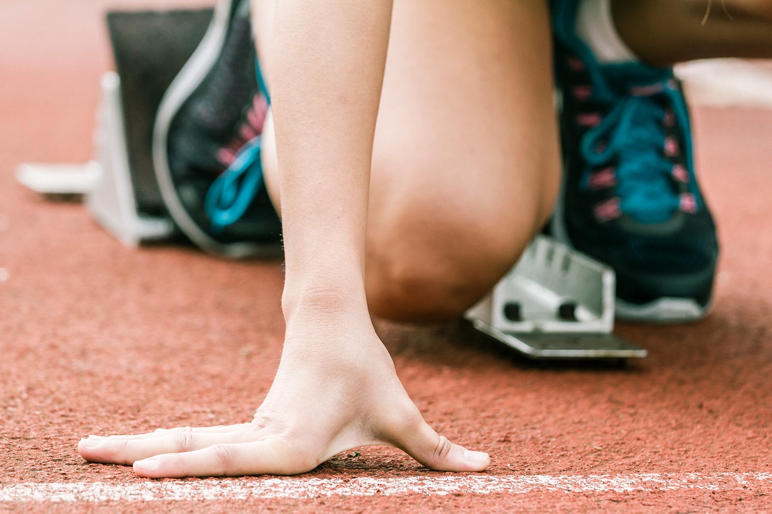 Close-up of a runner's hand as they prepare to sprint on a track